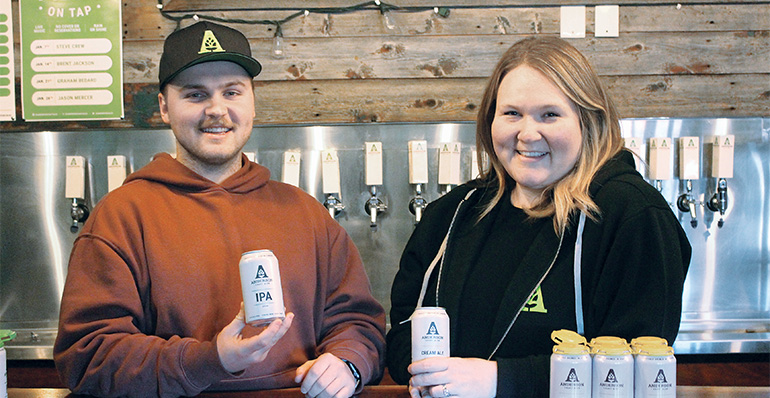 A photo of Keegan Padyk and Bridget Atkinson Fee posing with Anderson Ales beer cans