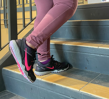A photo of a person in running shoes walking up a set of stairs.