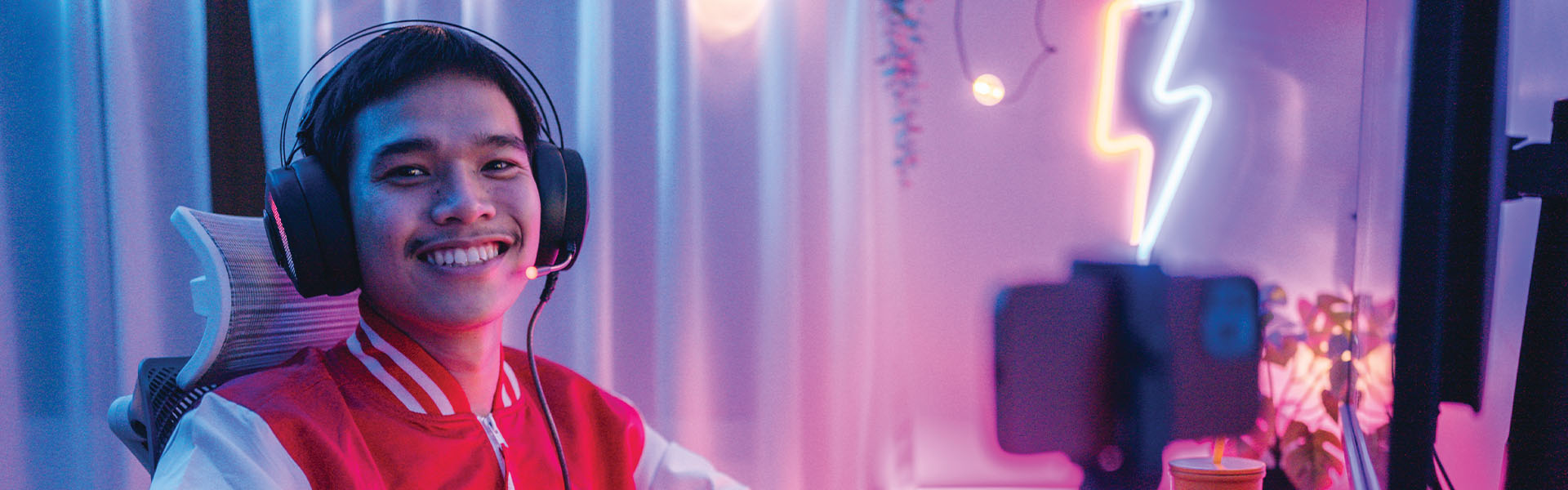 A stock image of a young person at a computer set-up wearing a gaming headset.