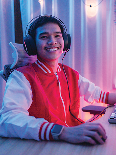 A stock image of a young person at a computer set-up wearing a gaming headset.